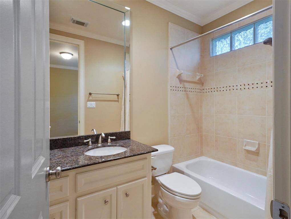 Here's the en suite bath to the 3rd floor bedroom. Features include a custom site-built vanity, granite countertop, crown molding, a shower/tub combo with a glass block clerestory window that allows natural light to filter in.