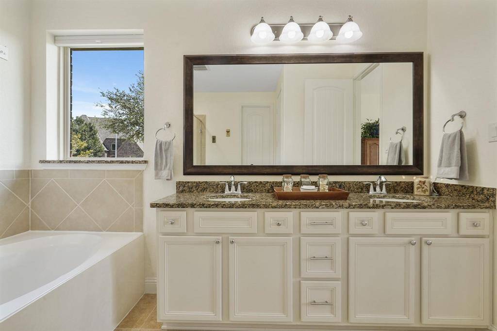 This primary bathroom is definitely move-in ready! Featuring a spa like oversized jetted garden tub, double sinks, light stained cabinets with granite countertops and modern finishes.