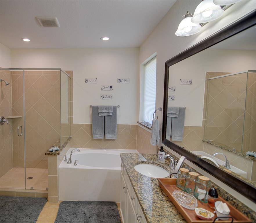 This additional view of the primary bath showcases the spacious walk-in shower with tile surround and a separate jetted garden spa like tub perfect for soaking after a long day.