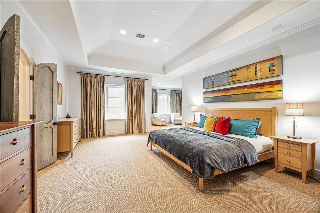 Luxurious primary suite with a serene sitting area, featuring two large windows that frame stunning views of the lush backyard and sparkling pool.