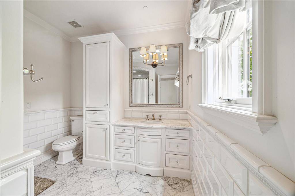 En-suite bath adjoins bedroom #3 and features white marble floors and a white marble vanity.