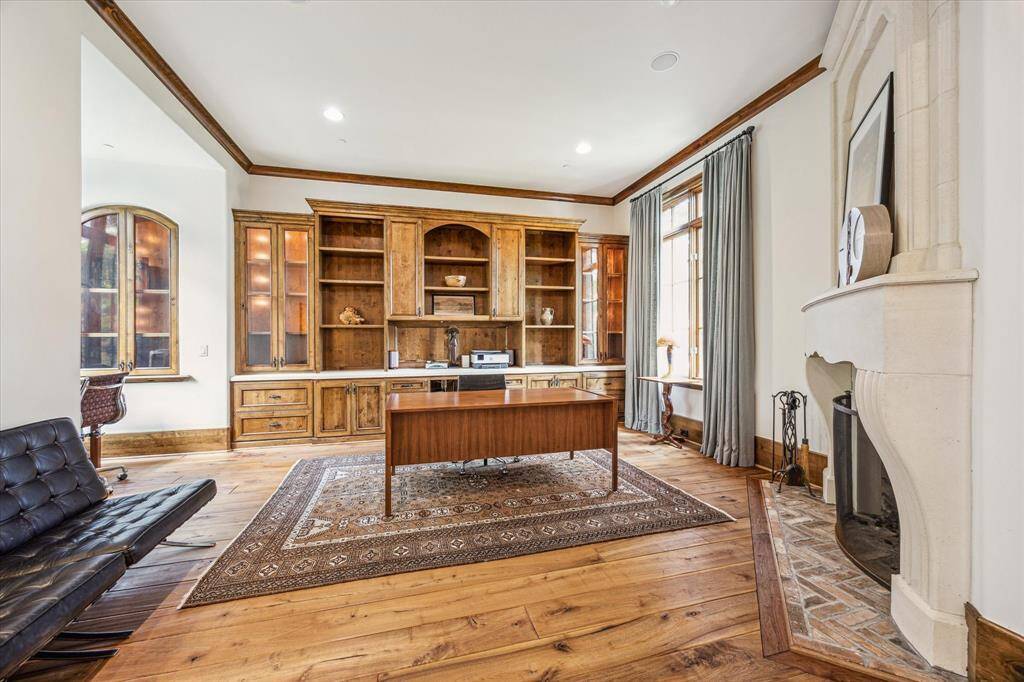 This expansive study offers a sophisticated retreat, featuring a gorgeous stone fireplace, elegant built-ins with glass-front cabinets and double glass pocket doors to ensure privacy when needed. Large windows offer serene views of the street and the lush backyard.