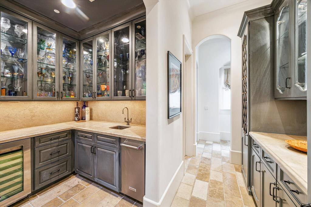 Butlers pantry with elegant built-ins. The walk-in wet bar is located to the left and features a serving bar, ice maker, and wine refrigerator. Straight ahead and to the left is a convenient family drop zone with built-ins, perfect for keeping everyone organized.