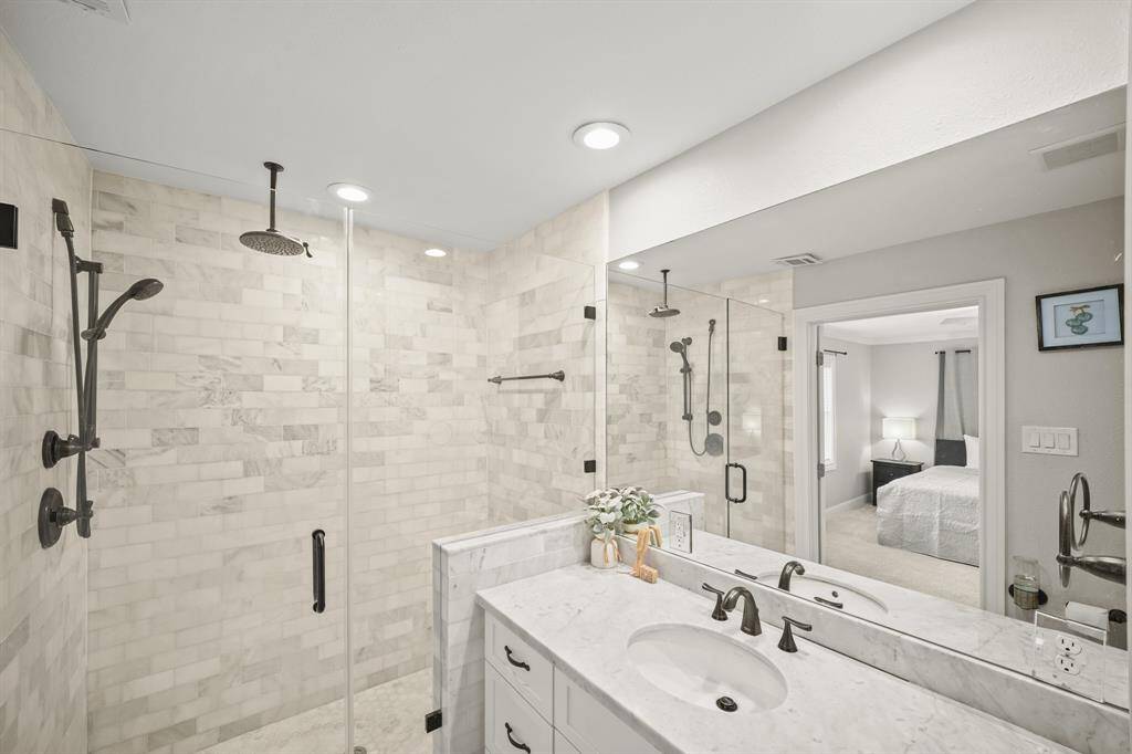 The Updated Primary Bath boasts a Marble Topped Vanity, White Painted Shaker Style Cabinets & Soft Close Drawers, White Porcelain Kohler Sink, Oil Rubbed Bronze Faucet, LED Recessed Lighting, Wall Mounted Mirror, Built in Linen Closet, Kohler Commode, & Grey Hued Wood Plank Porcelain Tile Floors. A Walk in Frameless Shower (Approx 5'6"x3'3") offers Marble Subway Tile Surround, Built in Bench, ORB Plumbing Fixtures with Hand Held Shower Wand, ORB Ceiling Mount Shower Head, & Hexagon Shaped Marble Tile Floor.