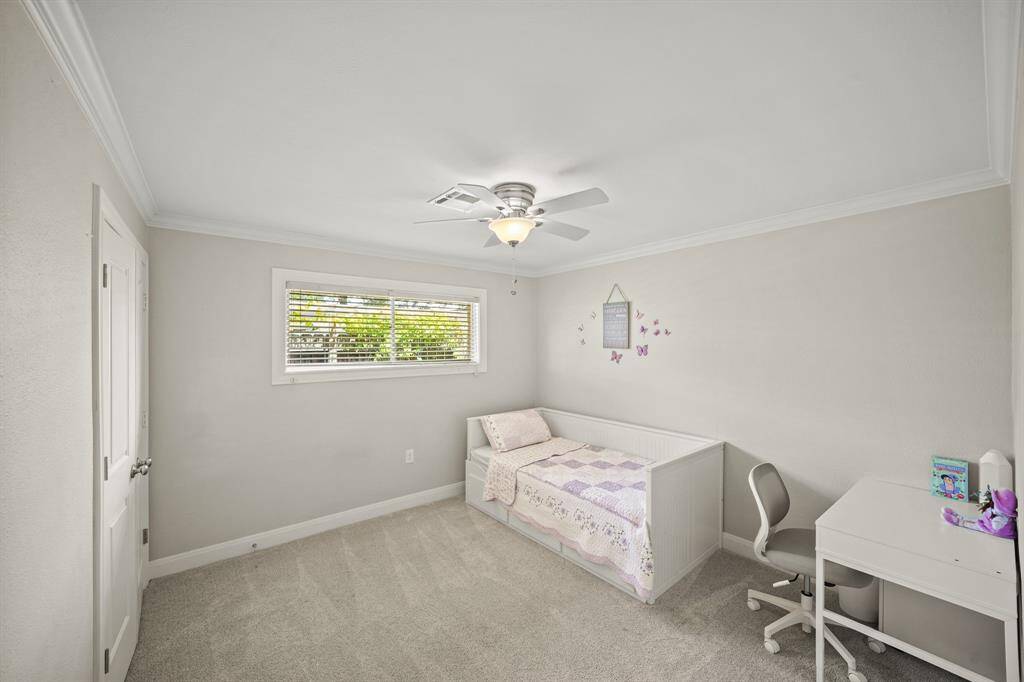 Amenities in the Third Bedroom include Light Grey Hued Pile Carpet, Crown Molding, Updated Polished Nickel Ceiling Fan with White Blades, Faux Wood Blinds, Light Grey Designer Paint with White Trim, and a Closet with Built in Shelf and Hanging Rod (Double Door Enclosure).