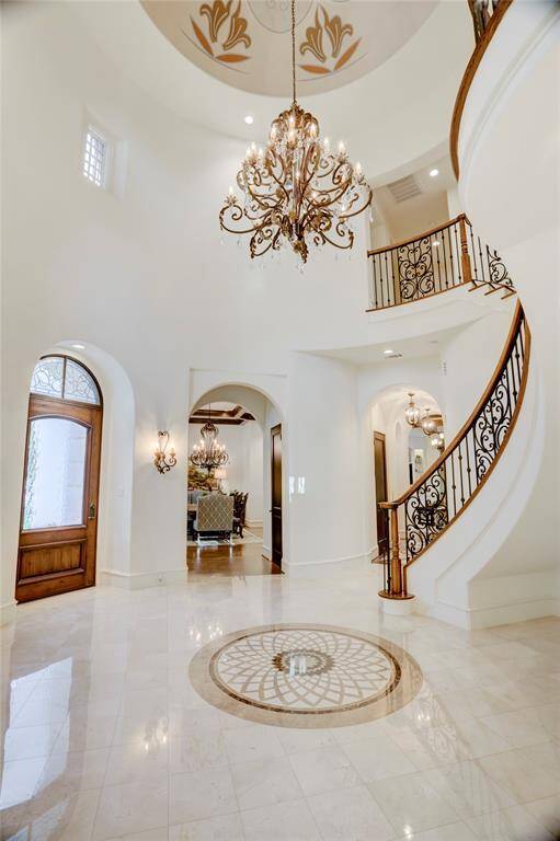 Grand rotunda entry with marble inlay floor, decorative domed ceiling, iron andcrystal chandeliers and sconces