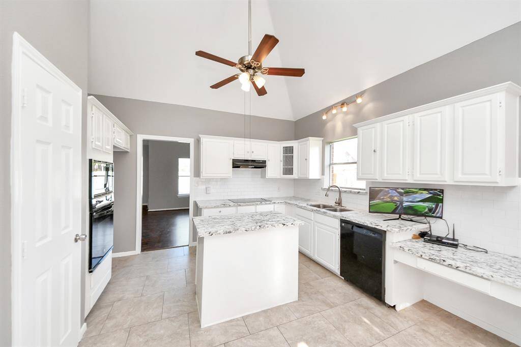 Bright kitchen with vaulted ceiling, white cabinetry, and granite countertops. Features a central island, modern appliances, and ample natural light.