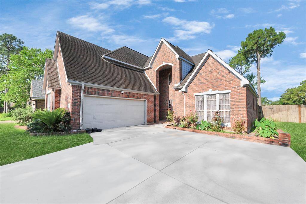 This photo showcases a spacious, modern brick home with a two-car garage, well-maintained front yard, and attractive landscaping. The driveway is wide, and the house features a distinctive roofline and large windows, offering a welcoming and stylish curb appeal.