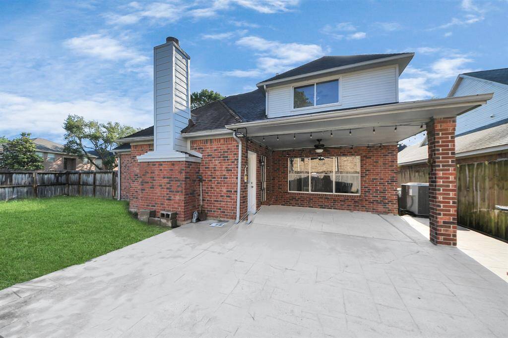 Charming brick home with a spacious, covered patio and a well-maintained backyard, ideal for outdoor entertaining or relaxation.