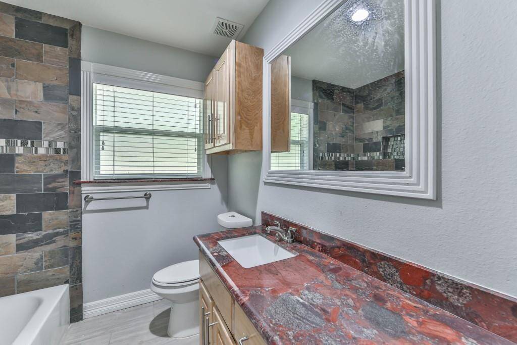Hall bathroom with the Red Marinachi granite, bath tub with slate surround, custom built maple cabinetry, & the continued theme of fluted architectural design...