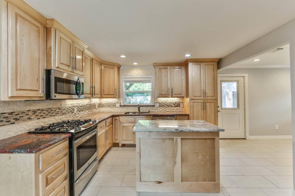 Red Marinachi slab granite covers the kitchen counters, while the kitchen island is topped by slab marble, providing beauty & space...