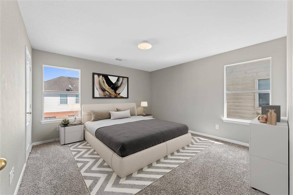 This second bedroom offers a peaceful retreat with plenty of space for rest and relaxation. The soft carpet underfoot and natural light streaming through the large windows create a cozy, welcoming atmosphere.