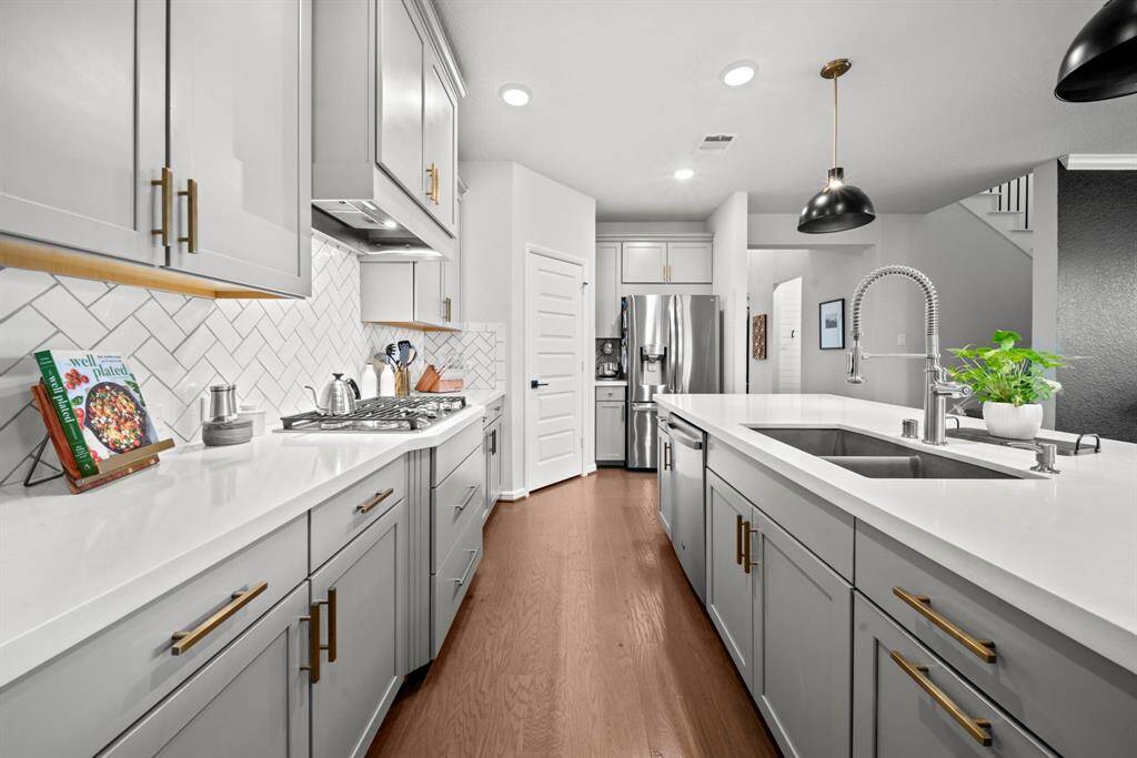 This kitchen is so sleek with its dove gray cabinets, chic cabinet hardware, upgraded faucet, granite composite sink, and upgraded pendant lighting. Walk-in pantry offers great storage.