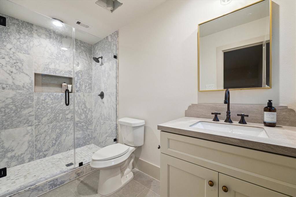 4th bedroom private bath, porcelain tiles, matte black fixtures, brass accents.