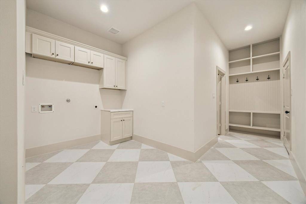 large gray checkered floor laundrette with storage, mudroom cubbies & pass-through to walk in pantry.