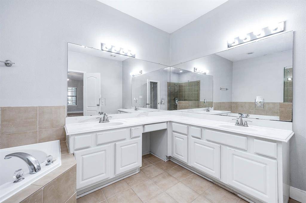 Primary bathroom boasting dual vanities, soaking tub and a separate shower