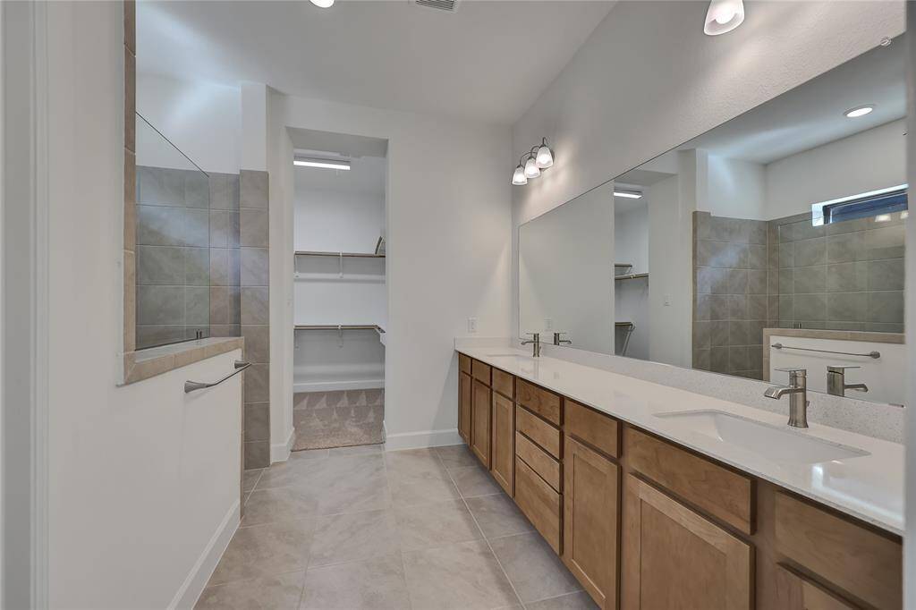 Praiseworthy Primary Oasisthat offers dual sinks, glassencased showered with tilesurround.