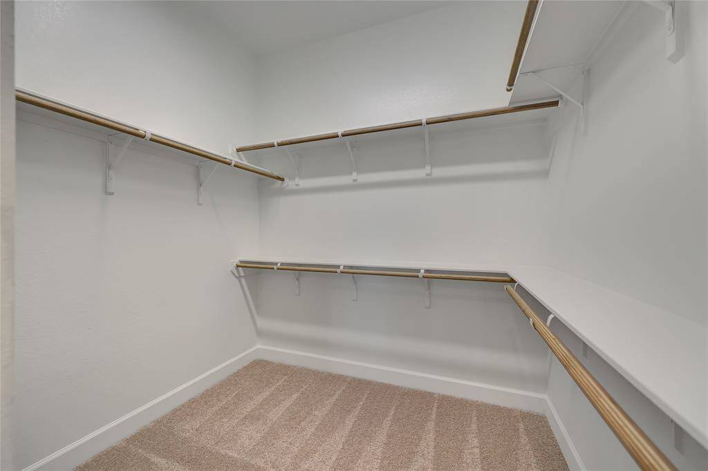 The primary closet features plush carpet and plenty of shelving for storage space.