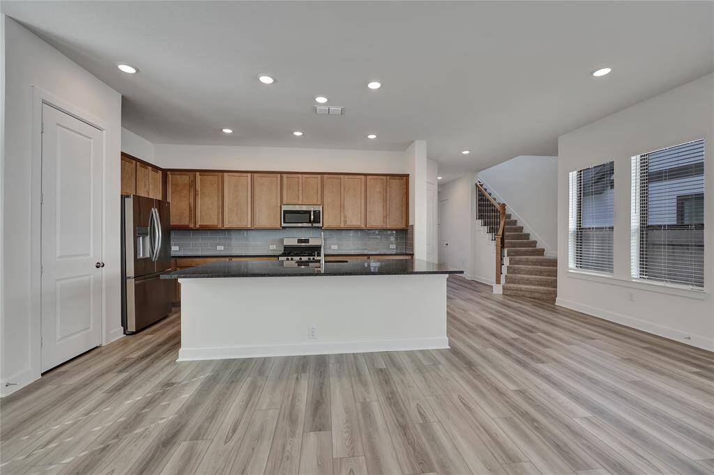 The kitchen offers customtile backsplash, modern appliances, island, and adjacentBlissful Breakfast Area.