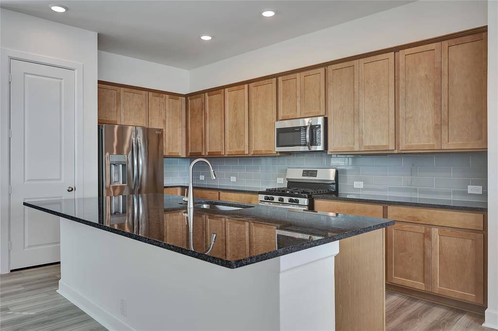 An additional view of this kitchen that alsooffers stainless steelappliances, gorgeous cabinetrythat wonderfully complimentsthe countertops and recessedlighting.