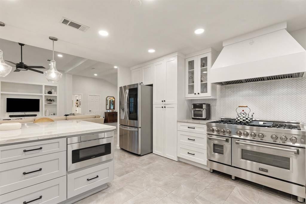 The professional-graze Z-Line 6 burner gas stove and range is not only incredibly functional, but is also a showstopper! Note the chevron patterned backsplash, modern and sleek vent hood, and glass front cabinets.