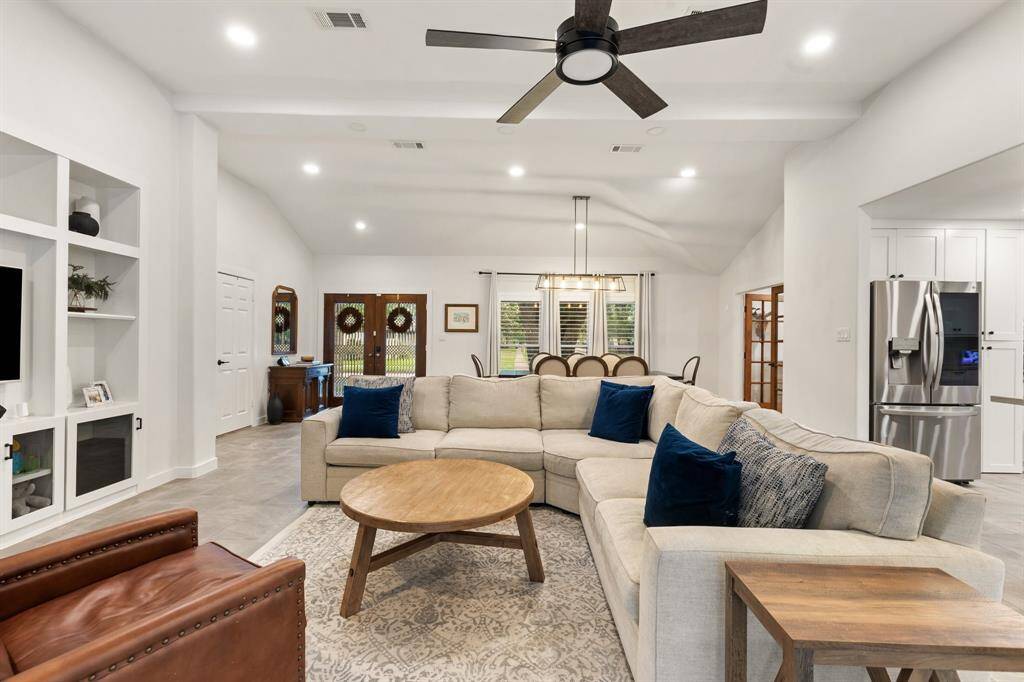 This large open living room offers built-ins, high ceilings, ceiling fan, french doors leading to the back patio and backyard, and premium tile flooring.