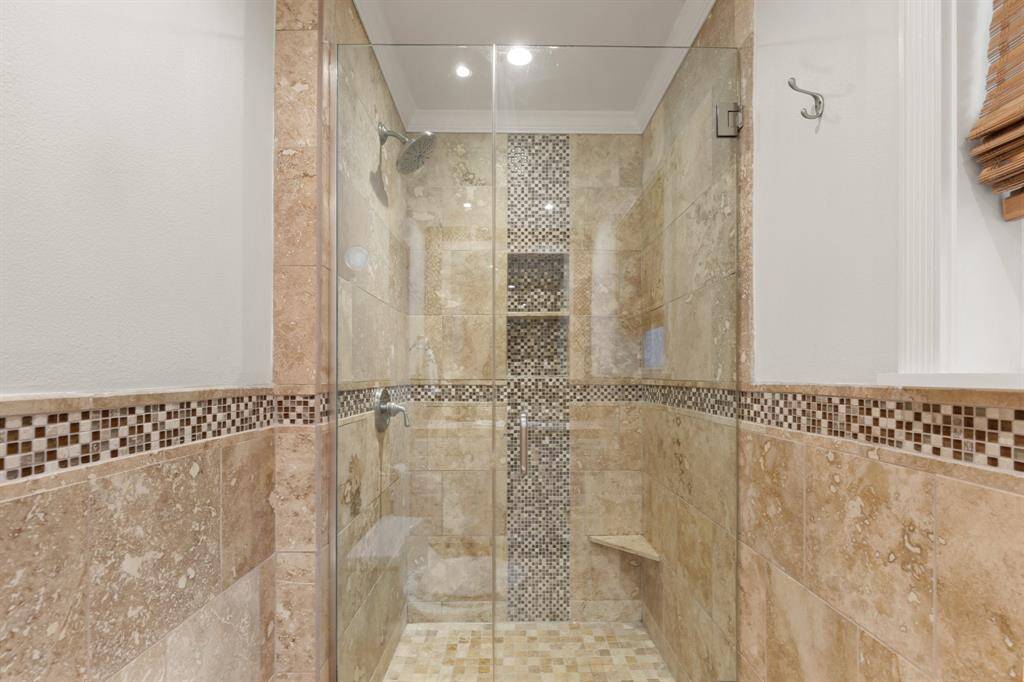 Primary bath has been enhanced with designer tile and an oversized freestanding shower with frameless glass.