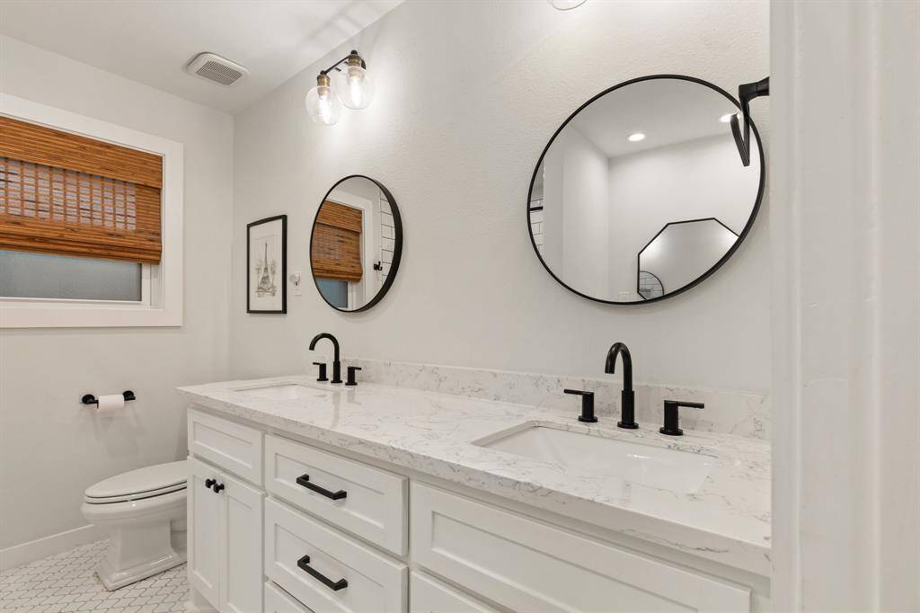 The secondary bathroom has been completely transformed with luxurious quartzite countertops, new bathtub and shower, and modern PEX plumbing. Also note the updated light fixtures, hardware, mirrors, and dual sinks.
