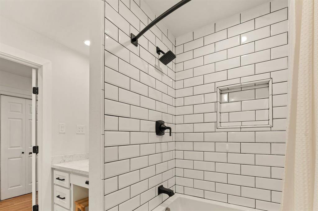Updated tile, new bathtub and shower, and shower storage niche add to the distinguished design of this bathroom.