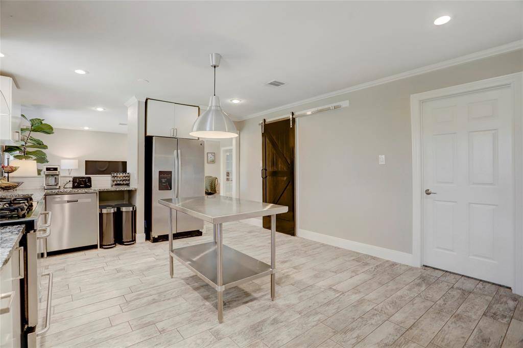 Room for an island workspace with pendant task light overhead. Barndoor for large walk-in pantry to keep everything organized!  Raised 6-panel interior doors with brushed nickel lever handles. This whie door leads to the indoor laundry room with storage cabinets.