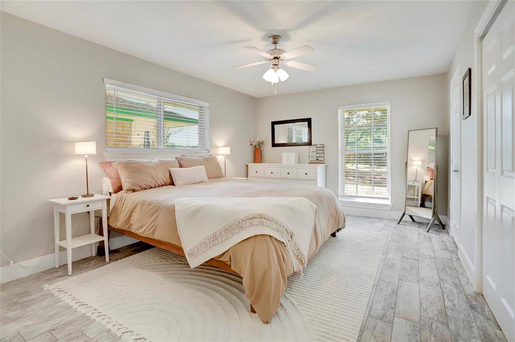 Large primary bedroom is light and bright!  Notice the King-sized bed & ceiling fan. This room also has 2 extra large closets!