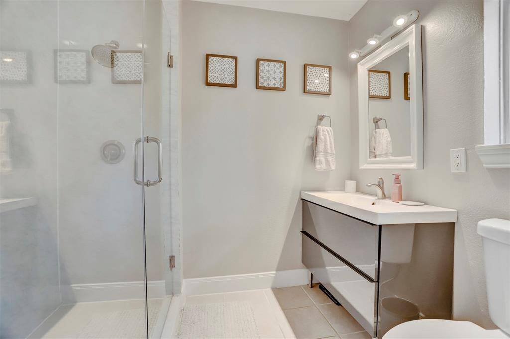 Sleek primary bathroom with Frameless Glass Shower with built-in bench. Toilet has dual flush!
