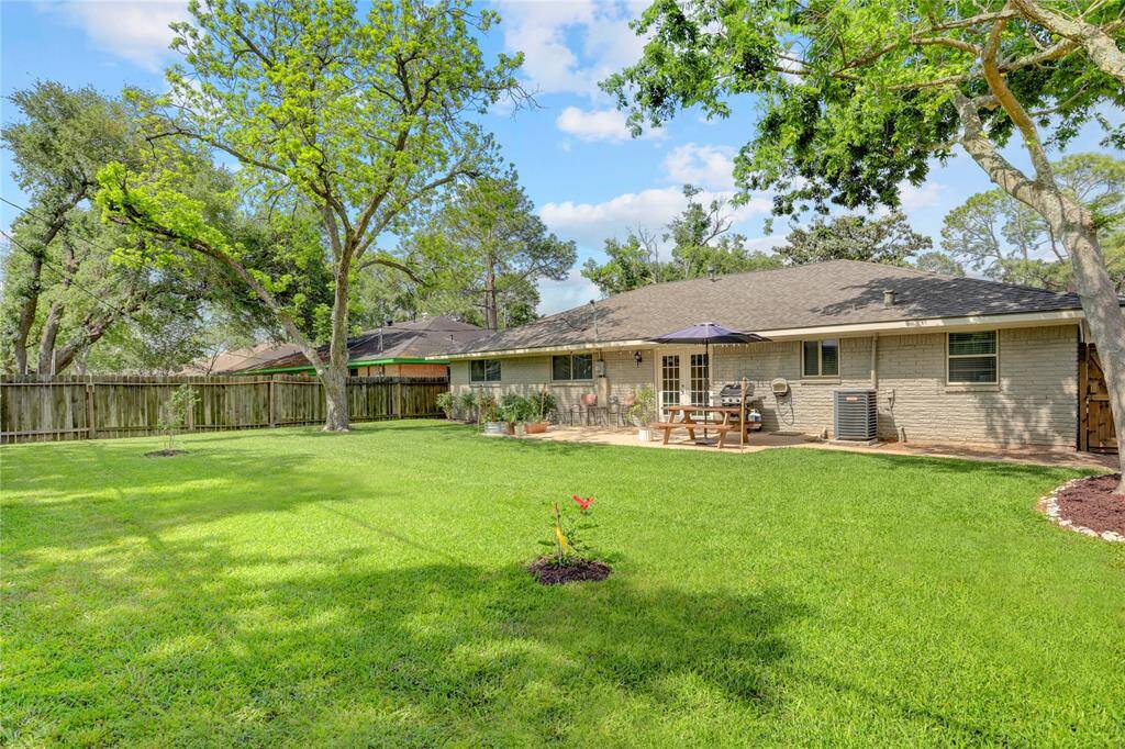 View of large backyard with mature pecan shade tree. Brick exterior on all 4 sides.