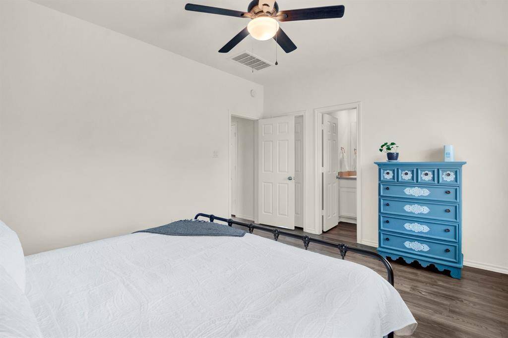 Bright and inviting bedroom featuring a ceiling fan. Enjoy the warmth of hardwood-style vinyl flooring and the convenience of an en-suite bathroom, creating a cozy and functional retreat.