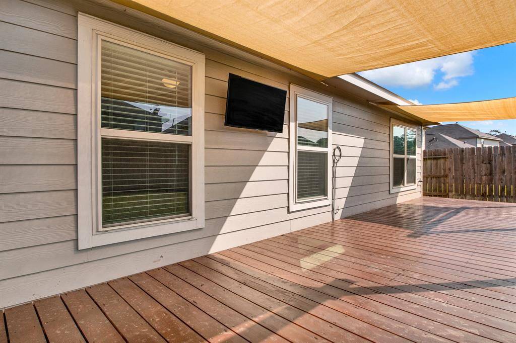 This photo shows a spacious wooden deck with shade sails, perfect for outdoor relaxation. Enclosed by a wooden fence, creating a private entertainment area.
