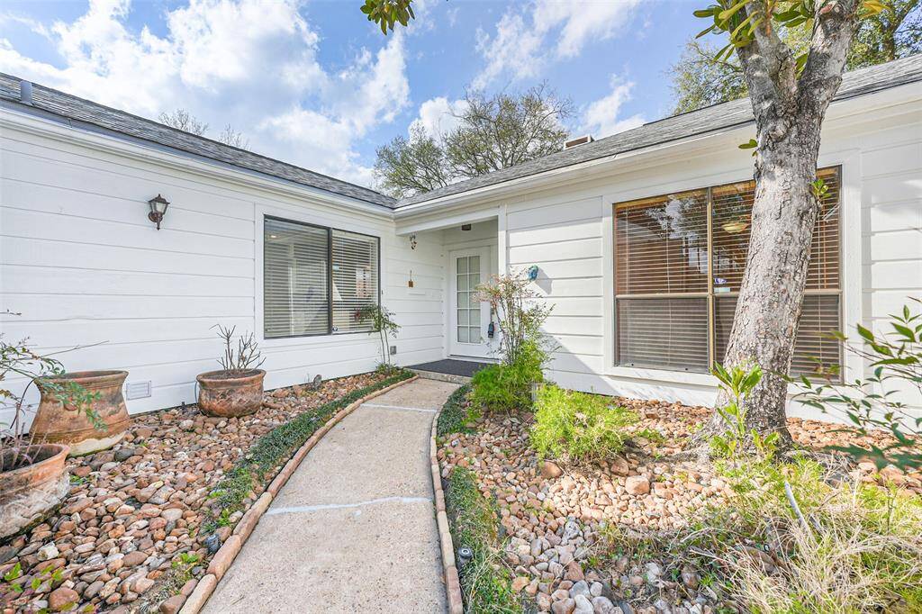 Inviting walkway, lush landscaping and mature trees greet you upon arrival