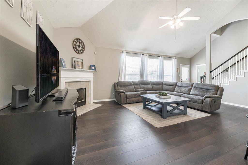 This inviting family room features soaring ceilings, durable luxury vinyl plank flooring, a cozy gas-log fireplace, and a wall of windows that fills the space with natural light. It's the perfect setting for relaxing evenings or casual gatherings with friends and family.