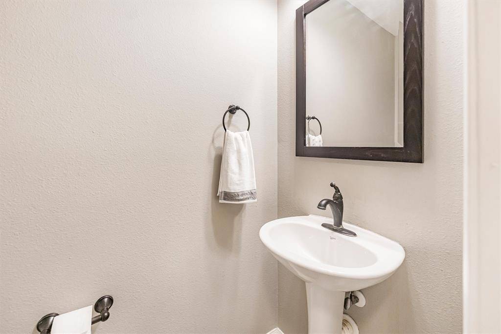 The first-floor powder bathroom is convenient for guests and offers a classic pedestal sink with a framed mirror above.