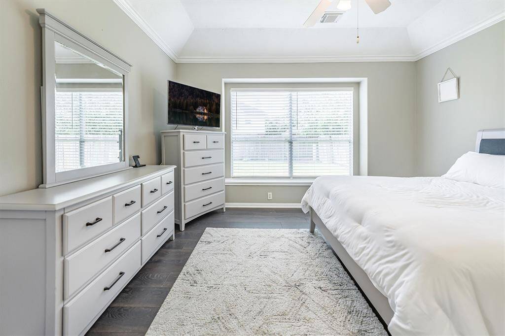 Start and end your day in this dreamy primary suite, where soft natural light pours through the picture window while elegant crown molding and warm LVP flooring set the tone for comfort and relaxation.
