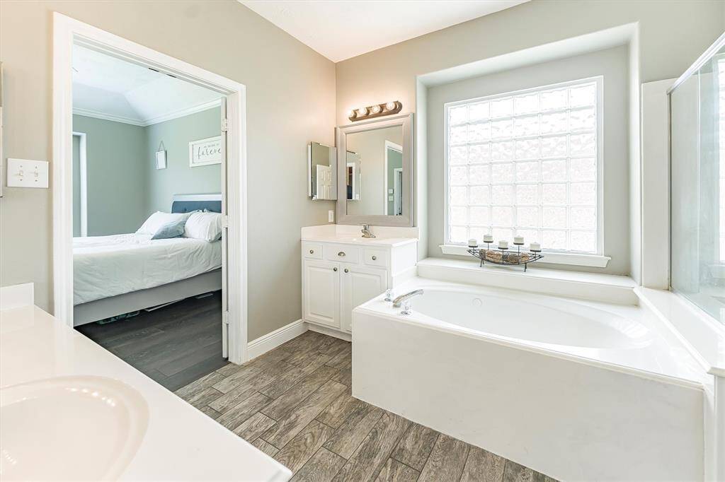 Natural light pours through the glass block window, casting a soft glow across this serene space. Gentle tones and spa-like finishes create the perfect setting to unwind and recharge.