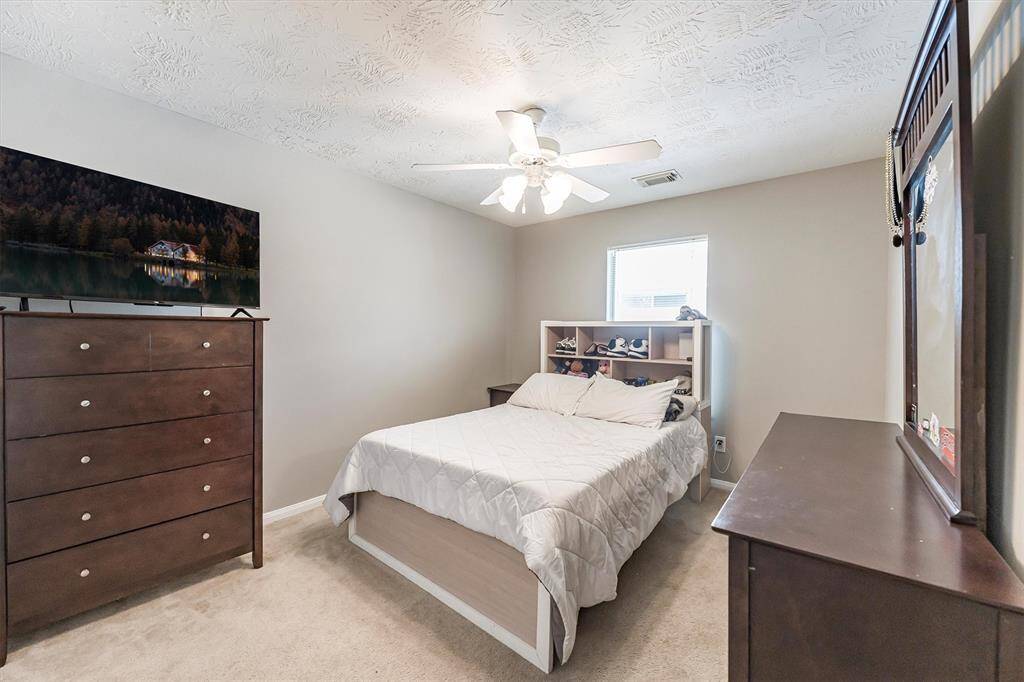 Family and guests will rest easy in this spacious guest room featuring soft neutral carpet and paint, a ceiling fan for added comfort, a large closet, and easy access to a full bathroom.