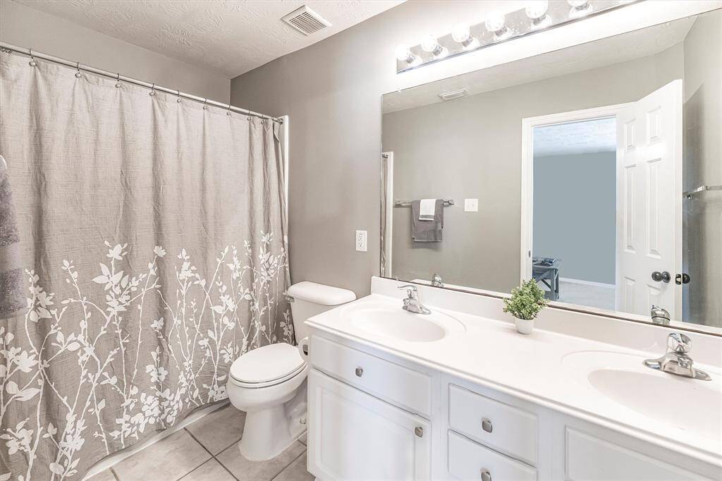 This full guest bathroom will be easy to share. It offers an extended dual sink vanity with a full width mirror and vanity lights above plus a convenient tub/shower enclosure.