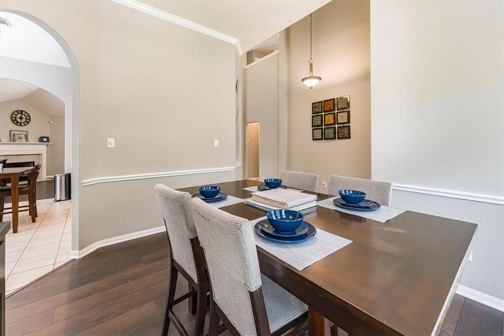 Your friends and family will love gathering in this elegant dining room featuring soft neutral paint, classic chair and crown molding, bay windows, a stylish chandelier, and beautiful luxury vinyl plank flooring.