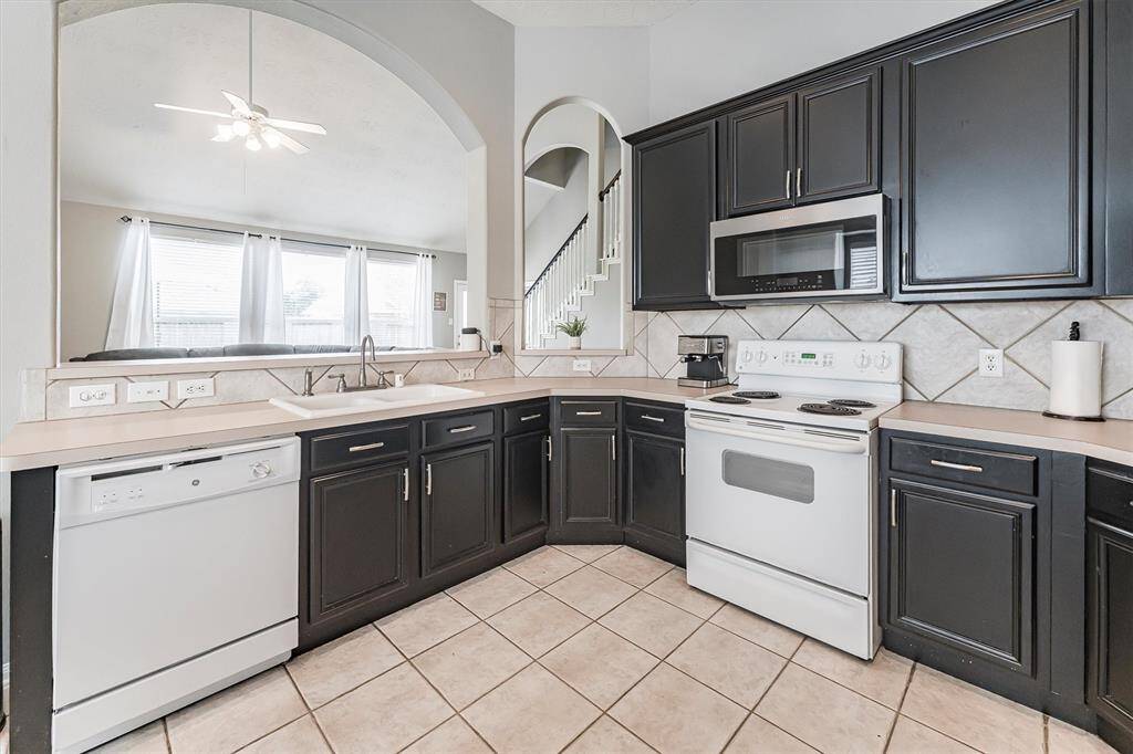 This open-concept kitchen keeps you connected, with arched pass-throughs offering clear views into the family room. Ample cabinetry, tile backsplash, and a wraparound counter make it both stylish and functional, perfect for cooking, serving, and socializing.
