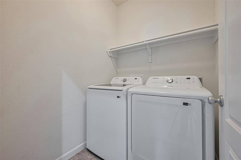 Laundry room with a washer and dryer side by side, and an overhead shelf for storage.