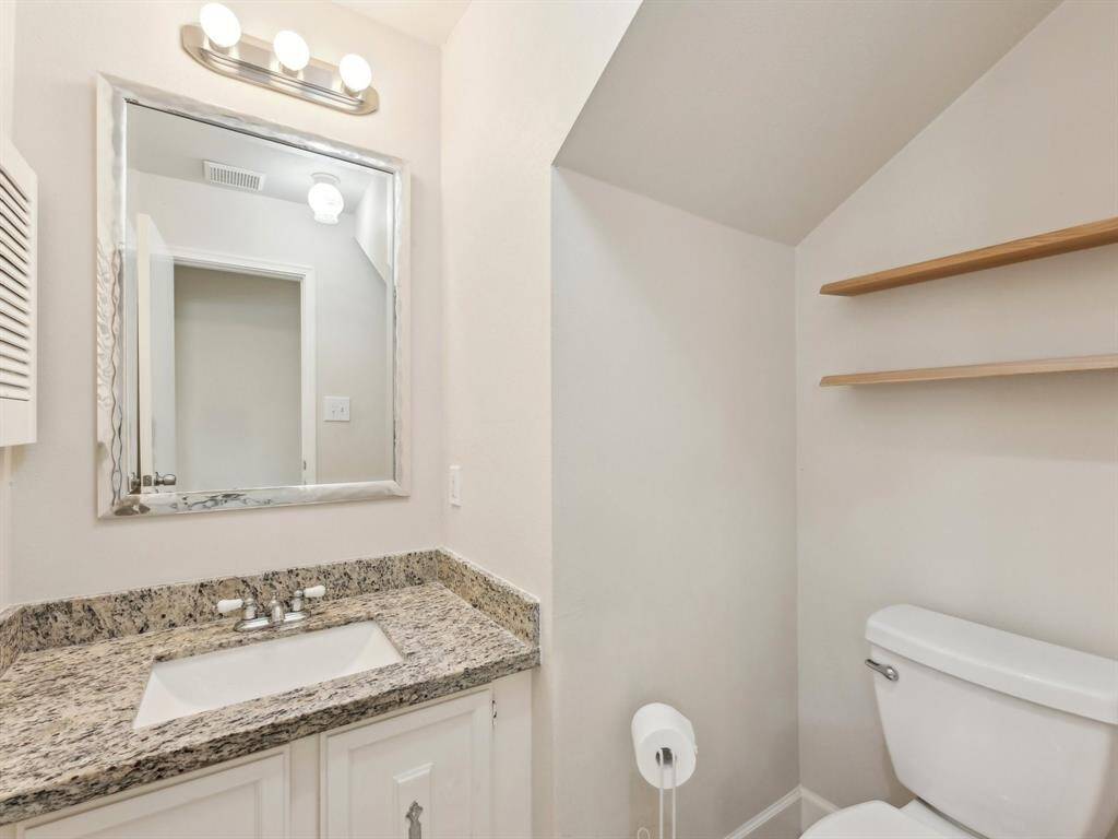 This Half Bath has a beautiful granite counter and floating shelving to store additional toiletry items.