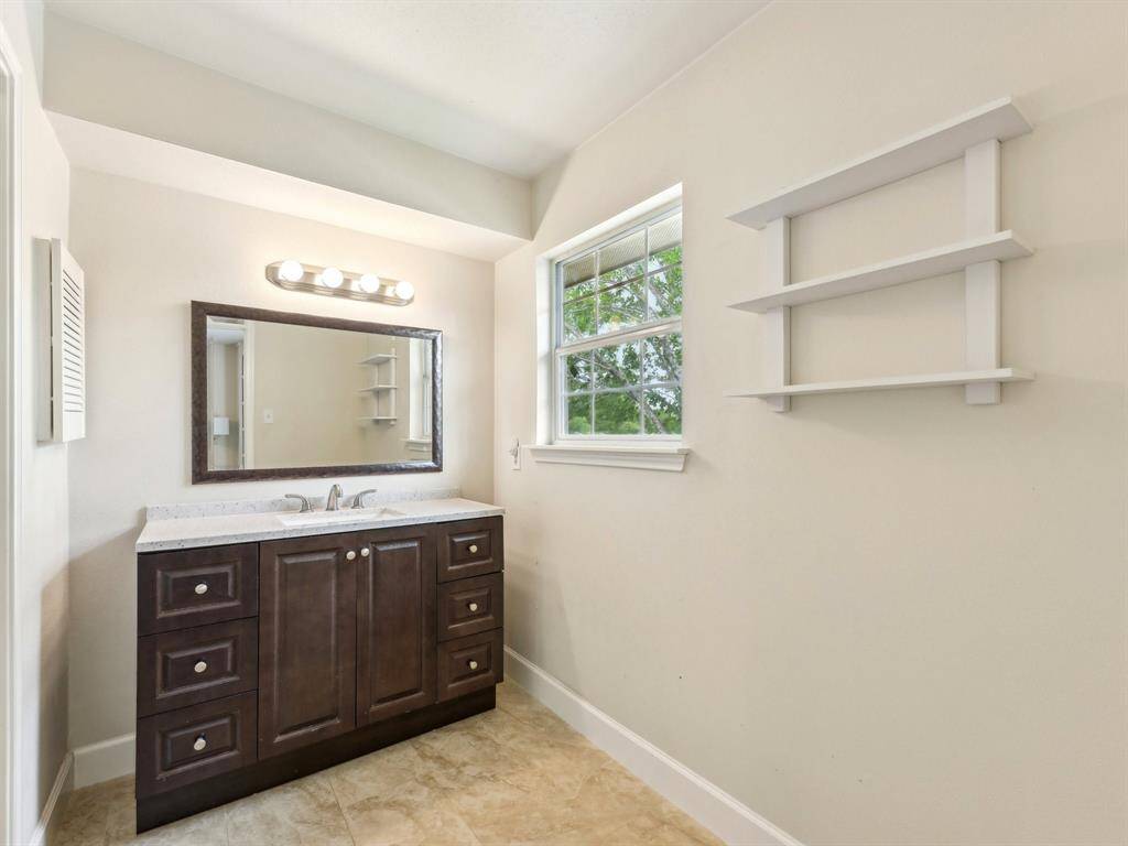 The ensuite for the Primary Bathroom has gorgeous, updated cabinetry, framed mirror, and shelving.