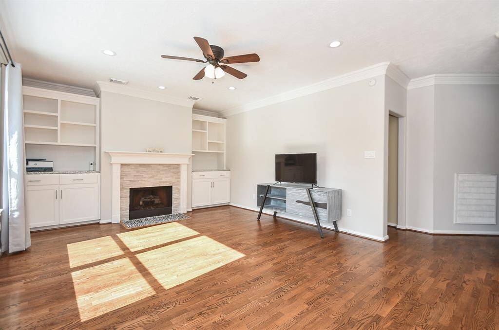 This fantastic living area gets great natural light, which enhances the generous built-in shelving/storage units on each side of the focal, brick encased fireplace. Pale neutral tones fill the walls with gorgeous laminate wood flooring. There is no carpet in the home.