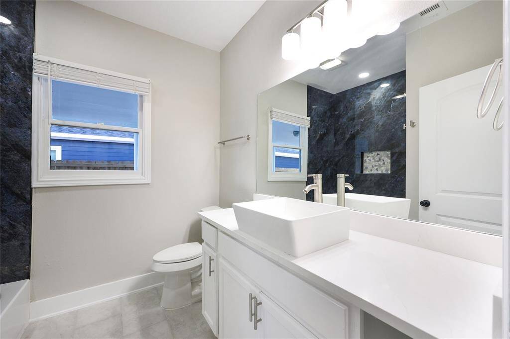 Secondary bathroom is also newly updated featuring a vessel sink, spacious vanity, and large mirror with contemporary lighting