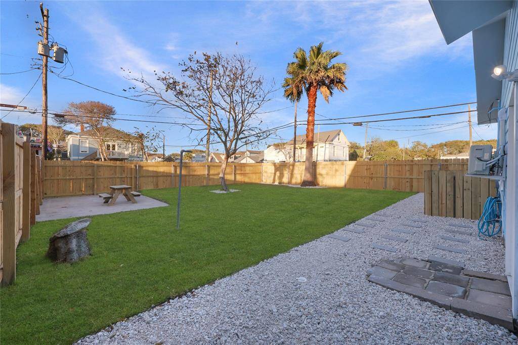 Spacious backyard featuring a green lawn, a gravel path, and a wooden privacy fence surrounding the property.